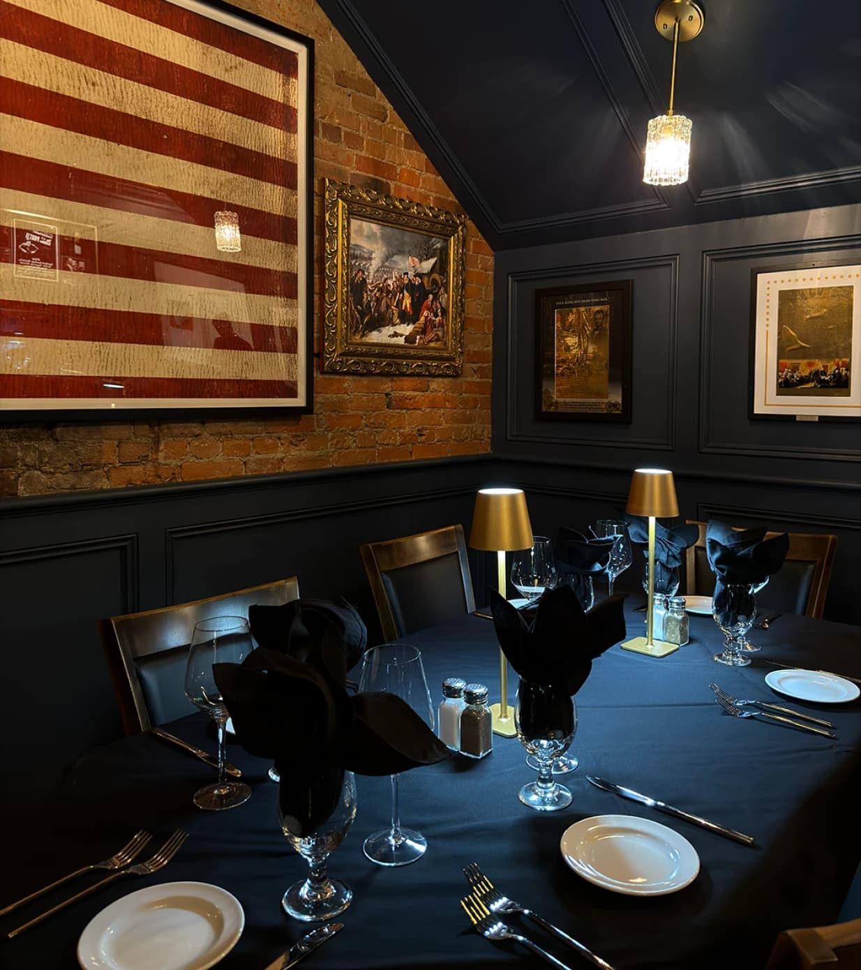 Intimate corner dining table with framed American flag, historical paintings, and warm lighting